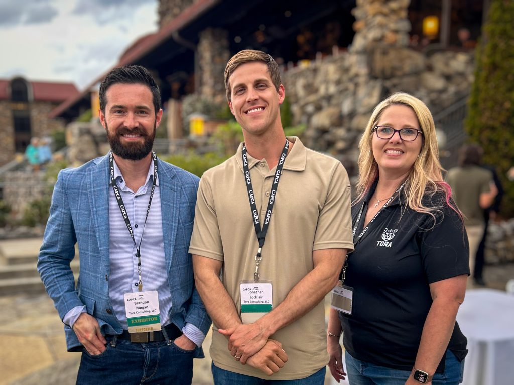 President Brandon Mogan, Senior Professional Advisor Jonathan Locklair, and Senior Advisor Alys Blair at an outdoor expo event in front of a stone building.